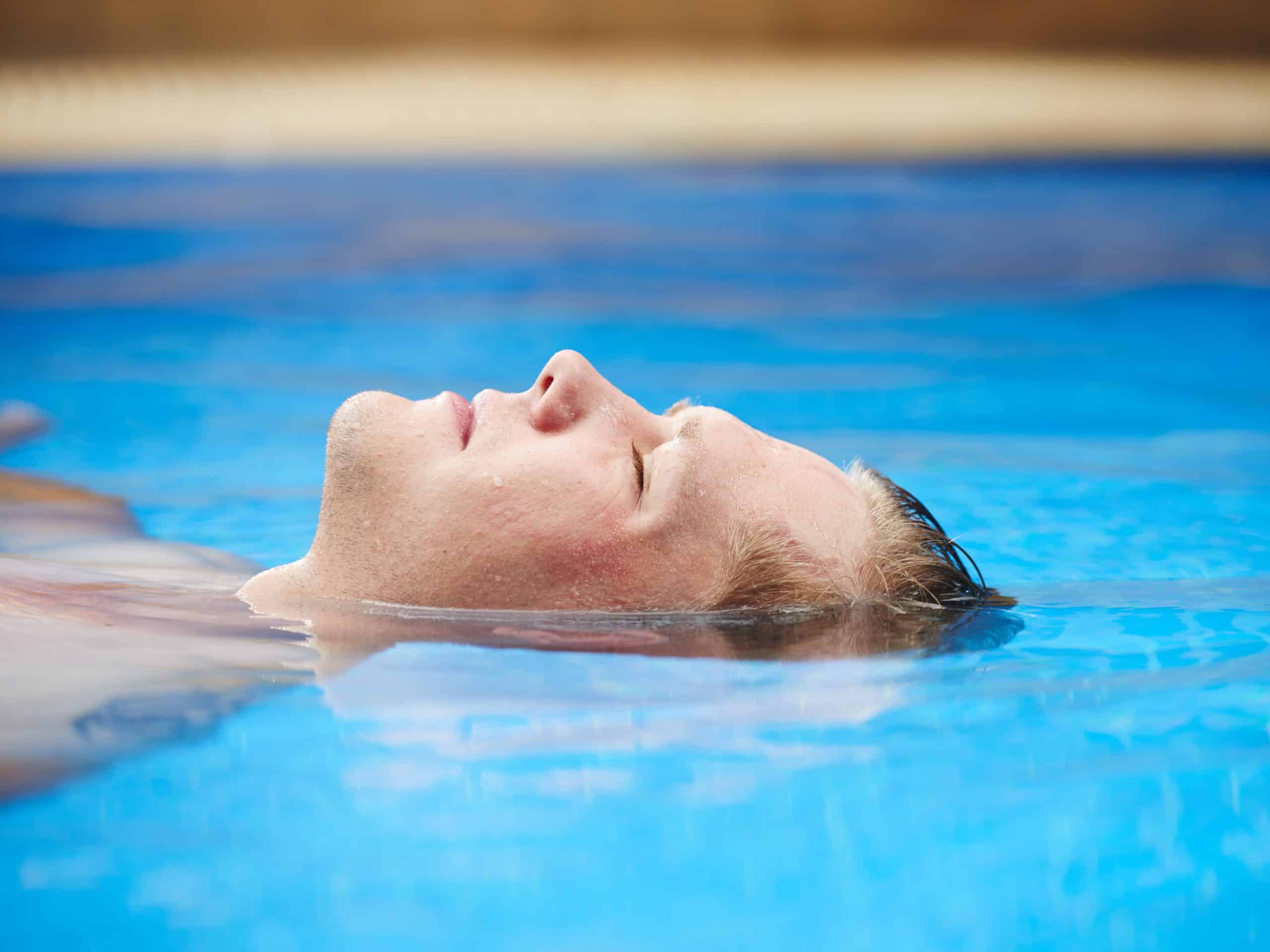 Face of man floating in pool with his eyes closed