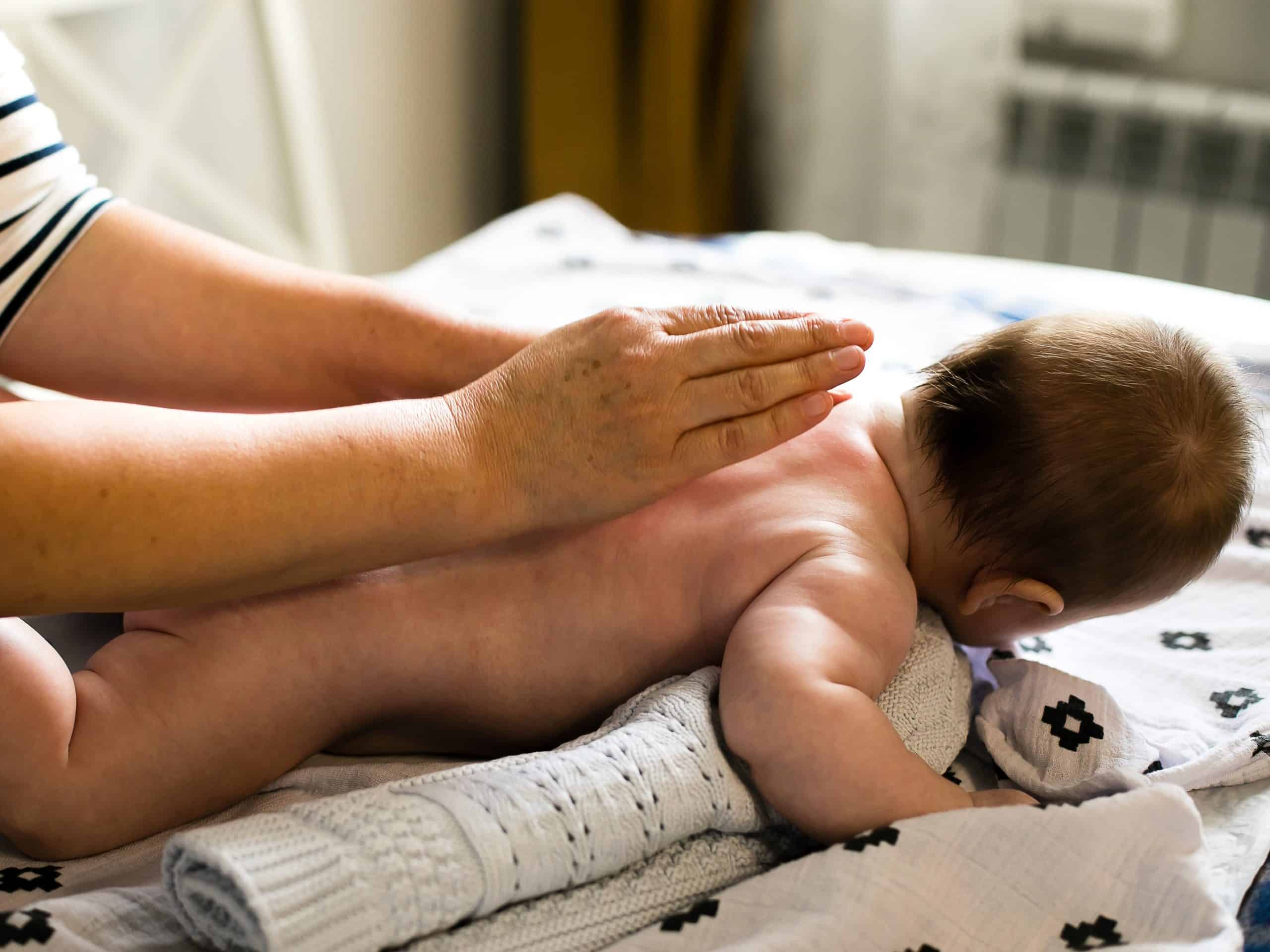 Mother makes newborn baby massage apply oil on the hand.