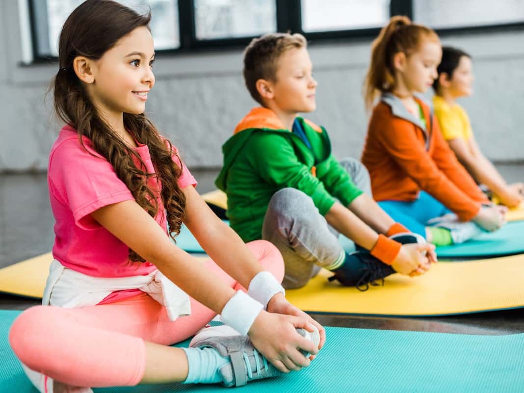 Smiling kids doing gymnastic exercises on fitness mats